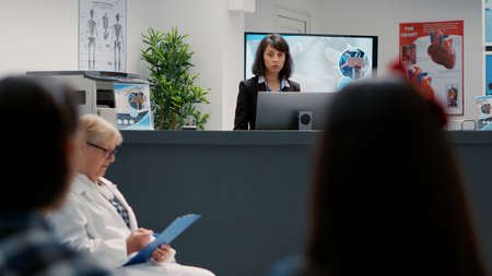 Portrait of hospital receptionist working at administrative counter to help patients with...