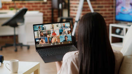 Woman working from home while discussing with manager on digital video call conference. Young adult...