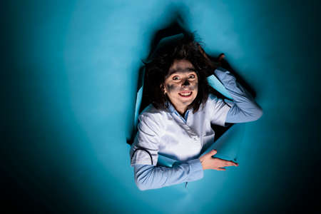 Insane scientist expert with amusing face expression and messy hair after failed chemical experiment. Silly crazy woman chemist with wacky look and goofy appearance after laboratory explosion.の写真素材