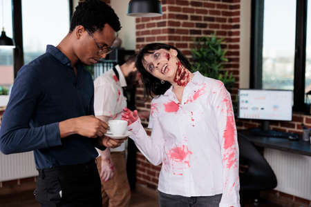 Spooky evil zombie talking to man at workplace, macabre cruel monster corpse in business office...