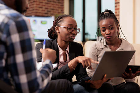 Coworkers team analyzing data on papers and laptop to plan online presentation with research information, sending email to manager. Doing teamwork collaboration to create company report files.の写真素材