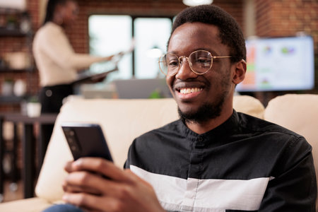 Male freelancer using mobile phone to browse internet website, creating business report and online...
