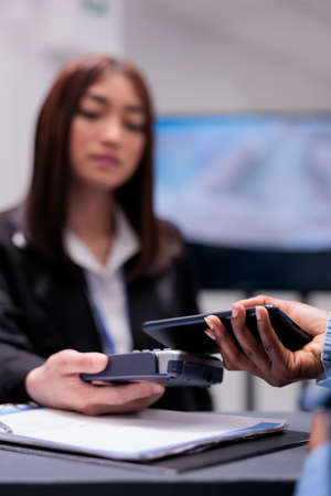 Young adult using credit card to pay checkup visit with specialist, paying for consultation and treatment at facility reception desk. Making payment after having examination appointment. Close up.の写真素材