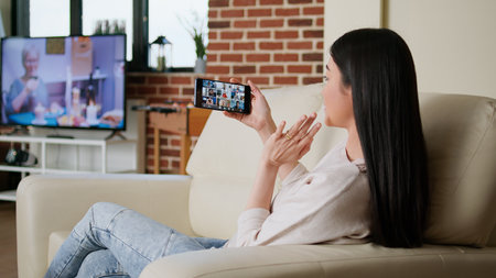 Woman working from home while discussing with coworkers on internet conference using smartphone....