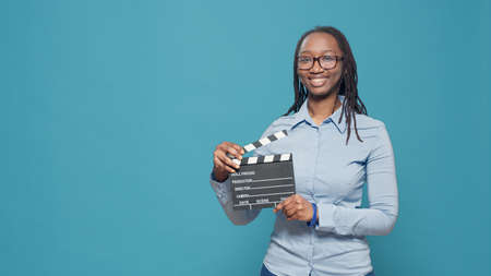 Portrait of african american woman holding film slate board used in movie and cinematography...