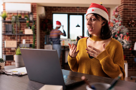 Company worker talking on videocall conference in office with christmas tree and festive...