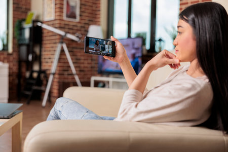 Authentic busy asian woman on video call meeting online communication workign from home talking mobile app waving hello internet technology happy call business freelancer talkの写真素材