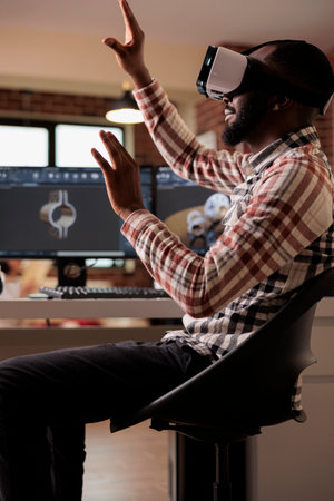 African american engineer manufacturing machine gears using vr glasses with 3d simulation and cad software on computer. Techinican developing industrial machinery product with interactive goggles.の写真素材