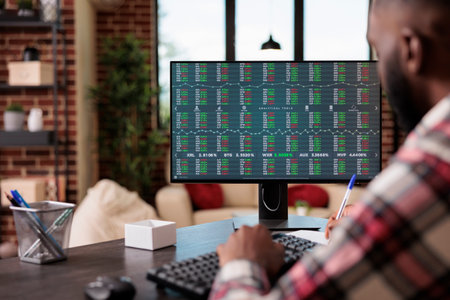 Financial trader working with stock market exchange on real time trade statistics, using computer...