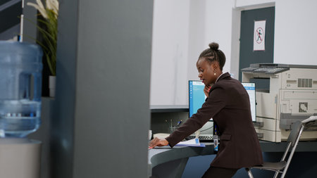 Medical worker answering landline phone call at reception desk counter, having remote conversation...