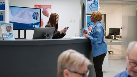 Young adult paying checkup consultation with credit card at clinical reception counter desk, having...