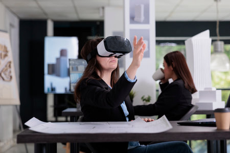 Architect in vr headset touching virtual building model, working on project in metaverse. Employee engineering in architecture office, real estate agency worker in augmented reality gogglesの写真素材