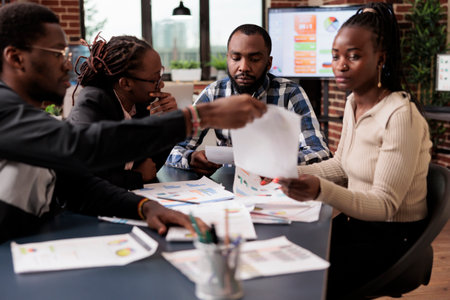Business people doing teamwork to plan project, analyzing information and data on documents. Using laptop and paperwork files to do research and create corporate presentation in office.の写真素材