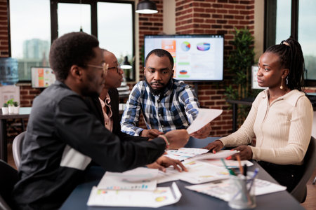 Startup employees doing teamwork to plan project, analyzing information and data on documents. Using laptop and paperwork files to do research and create corporate presentation in office.の写真素材