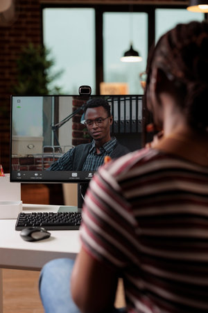 Freelancer talking with client on videoconference, back view, focus on computer monitor. Woman...