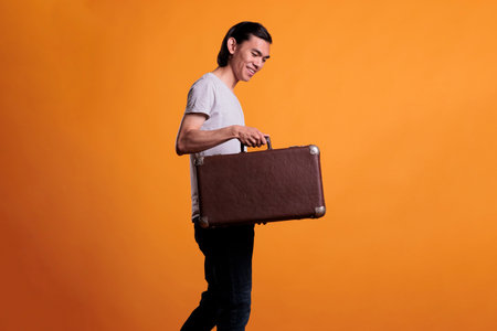 Happy young asian traveler holding suitcase, traveling, tourism concept. Cheerful smiling man...