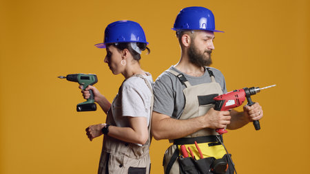 Team of engineers using power drill machine to screw nails and work on construction redevelopment in studio. Builders working with electric drilling nail gun on industrial demolition.の写真素材