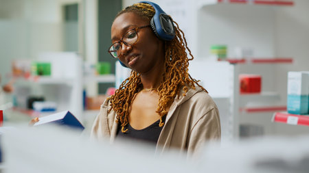 African american client examining boxes of medicine on drugstore shelves, looking at prescription on packages. Woman reading pharmaceutical products before buying drugs in pharmacy. Handheld shot.の写真素材
