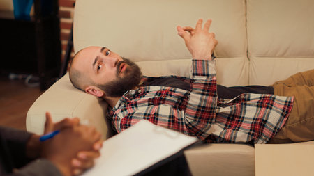 Displeased person complaining about marriage conflict at therpay session with counselor, laying on sofa. Talking about relationship problems and giving support in office. Handheld shot.の写真素材