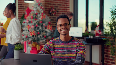 Portrait of employee analyzing research data on laptop during holiday season festivity in office. Working on computer and celebrating christmas eve with seasonal ornaments and decor.の写真素材