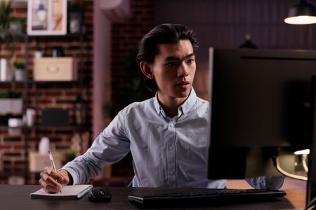 Male employee taking notes on files, working on paperwork documents to plan business report remotely...