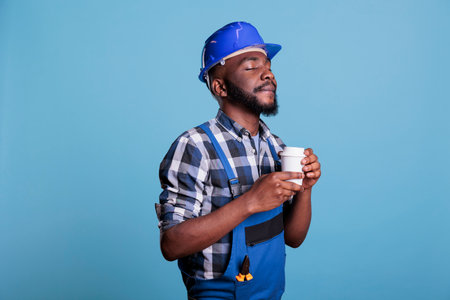 Relaxed construction worker enjoying a cup of favorite coffee before starting work on an interior...