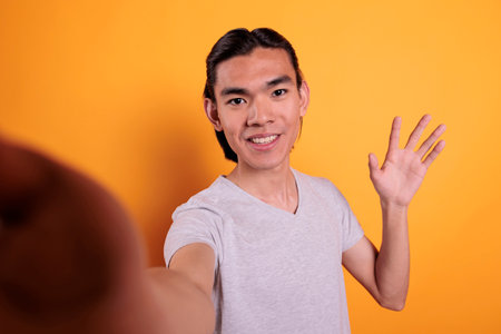 Smiling young man talking on video call first person view. Remote communication pov, online meeting on mobile phone, attractive cheerful person chatting on teleconference fpvの写真素材