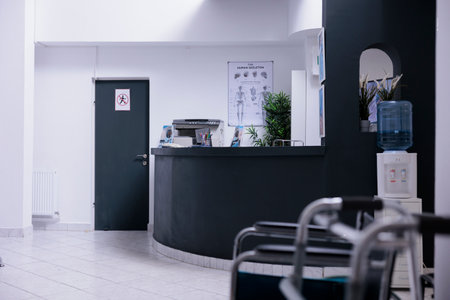 Desk without receptionists in empty hospital admitting room. Unoccupied information module with unused furniture in sanatorium lobby with no doctors or nurses. Empty emergency room with no health professionals.の写真素材