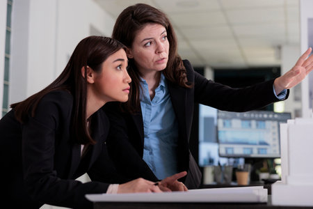 Architects working on building architecture draft, discussing 3d model, brainstorming on meeting. Engineers thinking on construction project sketch, looking at blueprints in coworking spaceの写真素材