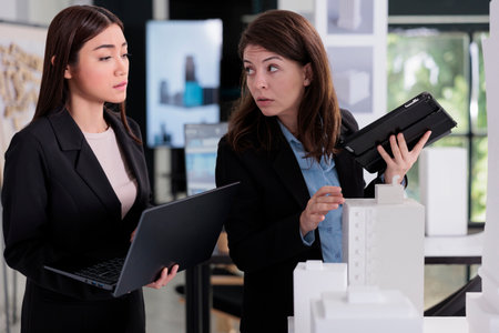 Architects communication, engineers holding laptop, working with building construction project in...