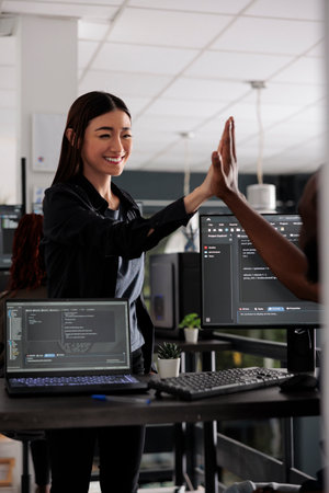 Diverse successful web developers celebrating code compiling, doing highfive hand gesture after...