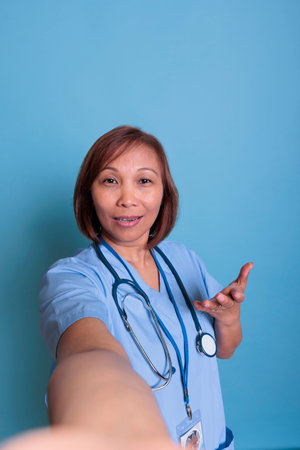 Medical assistant talking with remote practitioner doctor during videocall telehealth meeting discussing healthcare treatment. Asian nurse working at illness expertise during checkup visitの写真素材
