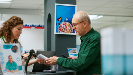 Senior client using telephone and nfc payment to buy pharmaceutics and prescription medicine at drugstore. Elderly man paying medicaments and bottles of pills, buying pharmaceutical products.の写真素材