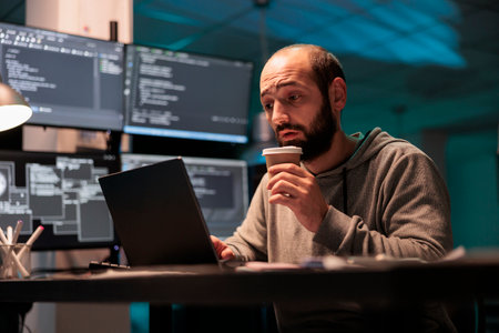 Overworked coder drinking coffee cup and programming html script in office after hours, enjoying caffeine beverage to finish developing source code. Tired programmer with drink.の写真素材