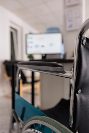 Close up view of wheelchair for person with disability workspace, background out of focus shot of desktop monitor with data analysis without people after work hours, disabled friendly office.の写真素材