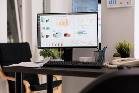Desktop computer running financial management software on office desk. Screen showing cost analysis software on screen. Specialized workplace with no people working on itの写真素材