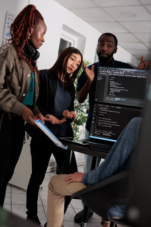 Multi ethnic engineer coding html script information on programming computer at desk, parsing source...