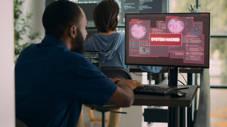 African american it engineer writing code encountering hacking alert on computer, dealing with unexpected system error and message flashing on screen. Cyber security development office.の写真素材