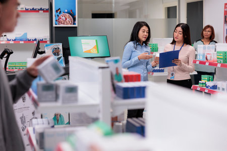 Medical consultant helping asian client with healthcare products, giving box of supplements to cure disease. Pharmacist talking to customer about pharmaceutical drugs and vitamins.の写真素材