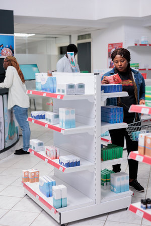 African american woman shopping in drugstore, checking prescription heart supplements, reading...