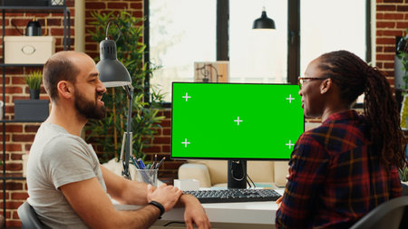 Diverse colleagues working with greenscreen display on computer, analyzing isolated chroma key on...