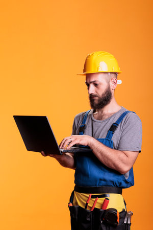 Young renovator using laptop to browse internet website, looking for renovating inspiration....