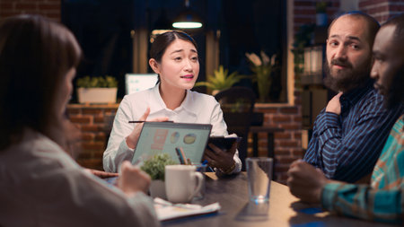 Asian woman speaking at table in business meeting, corporate presentation discussion. Coworkers...