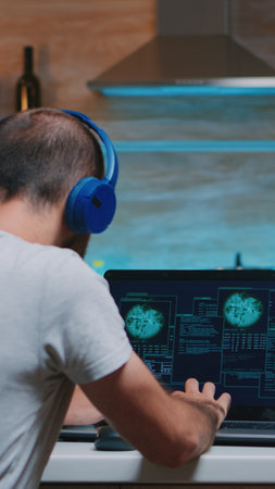 Remote man thief with headset stealing data from company hacking system from home. Programmer writing a dangerous malware for cyber attacks using performance device during midnight.の写真素材