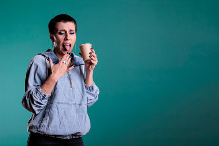 Portrait of beautiful woman holding cup of coffee drinking hot beverage making negative expression...
