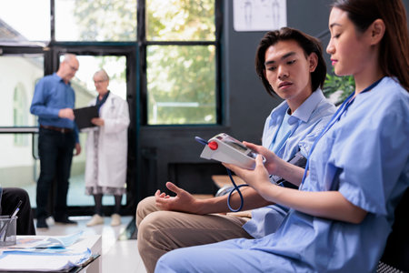 Asian medical assistant measuring patient blood pressure and hypertension with tonometer instrument...