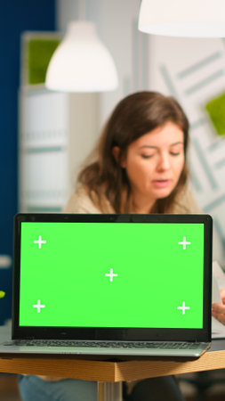 Group of business people discussing company plan with mockup laptop in front of camera, pc ready for financial project presentation placed on desk. Leader using green screen pc with chroma key displayの写真素材