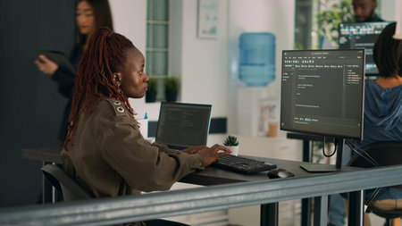 African american coder writing programming language on computer to develop new user interface. System egineer programming html database script in it software development agency. Tripod shot.の写真素材