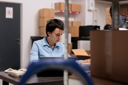 Storehouse manager sitting at desk table looking at cargo stock before start preparing clients...