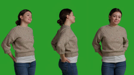 Close up of young adult posing over green screen backdrop, standing on greenscreen isolated template. Female model looking natural and confident, acting optimistic and smiling on camera.の写真素材